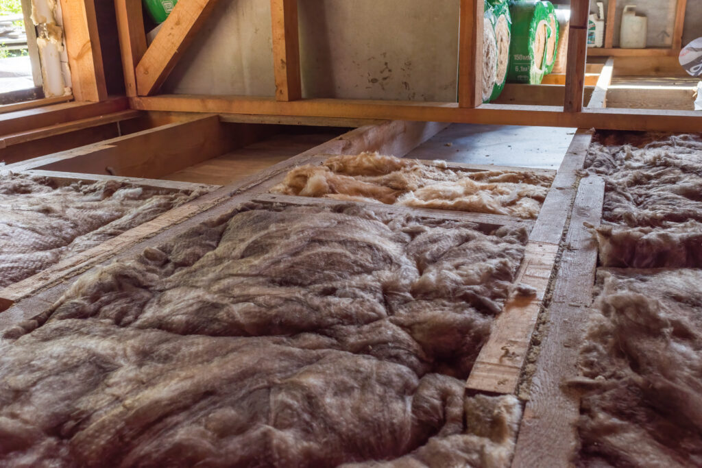 laying insulation on the floor in a frame house under construction. natural light.
