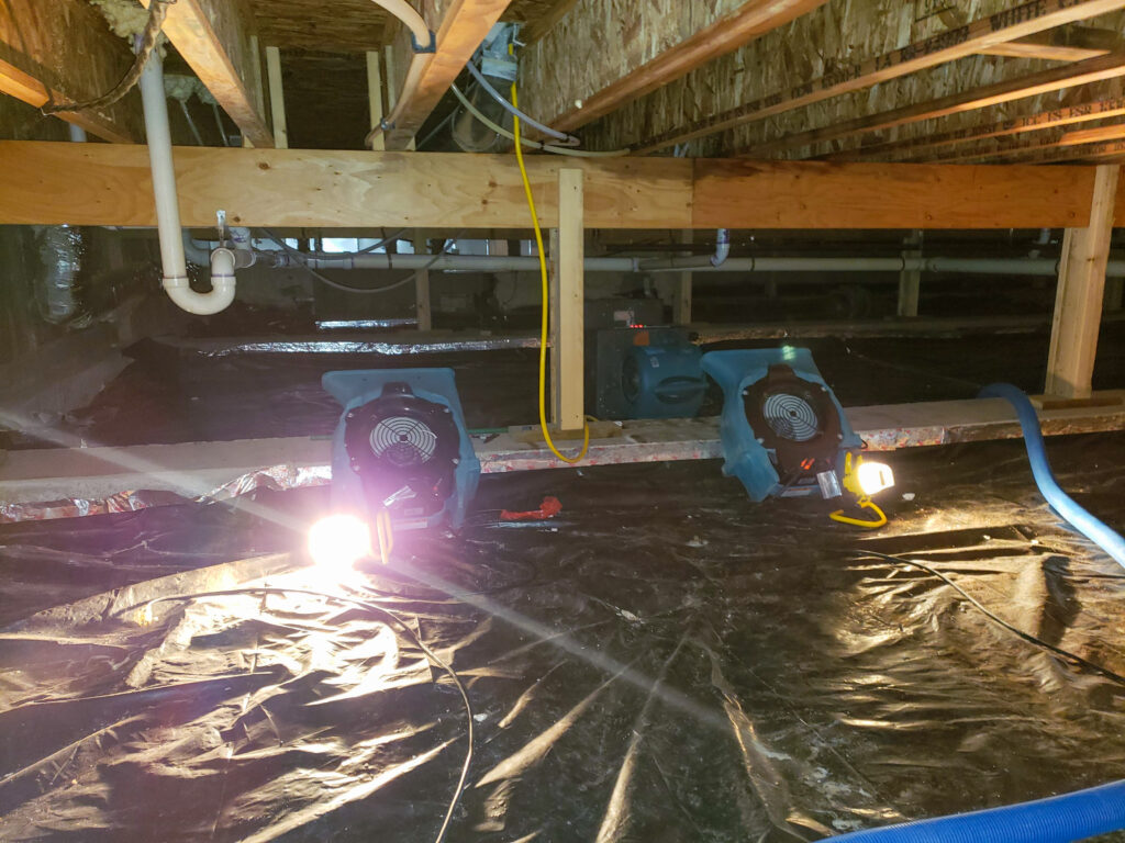 Fans drying water damage in a crawl space