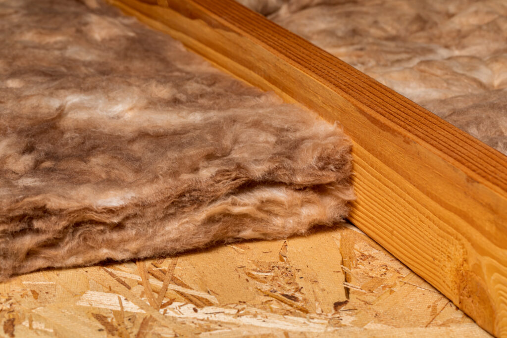 Fiberglass attic insulation installed between wooden joists, illustrating typical residential insulation used to improve energy efficiency.