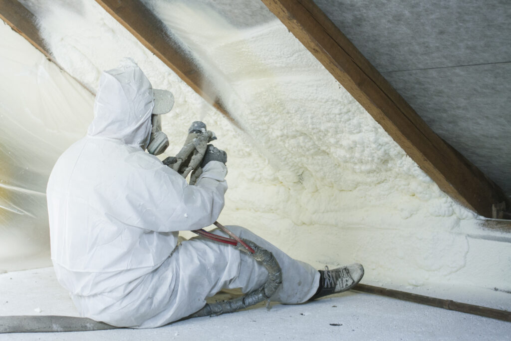 a technician spraying spray foam in an attic.