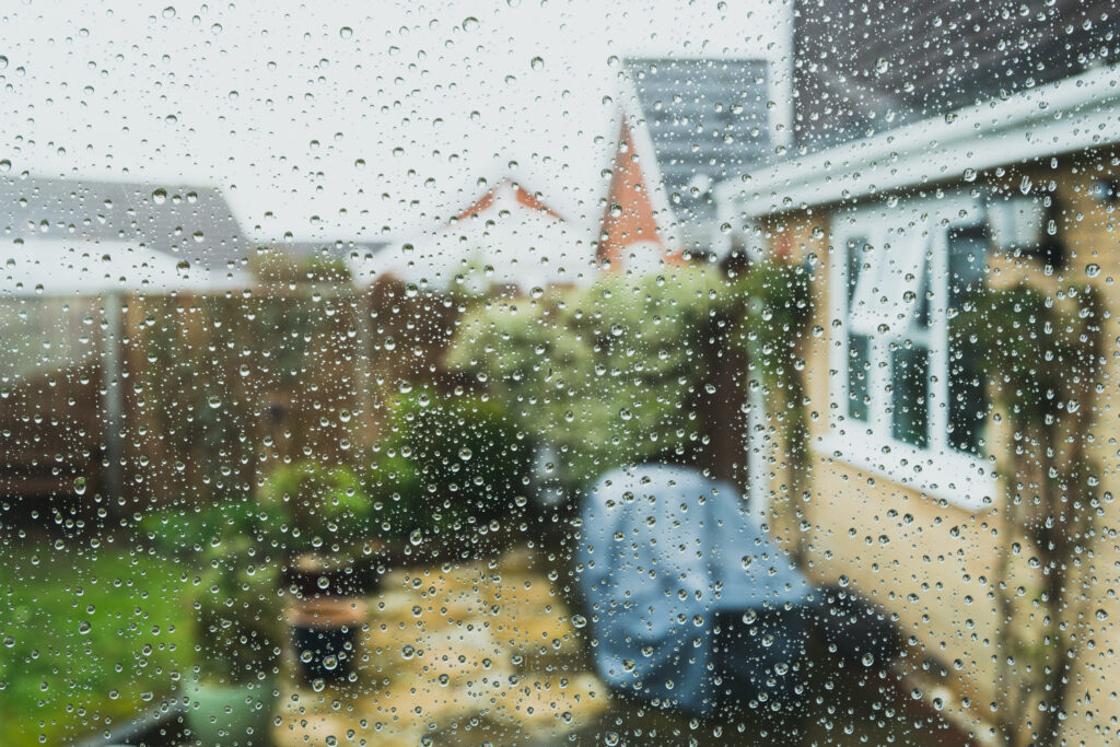 Raindrops on a window overlooking residential homes during rainy weather